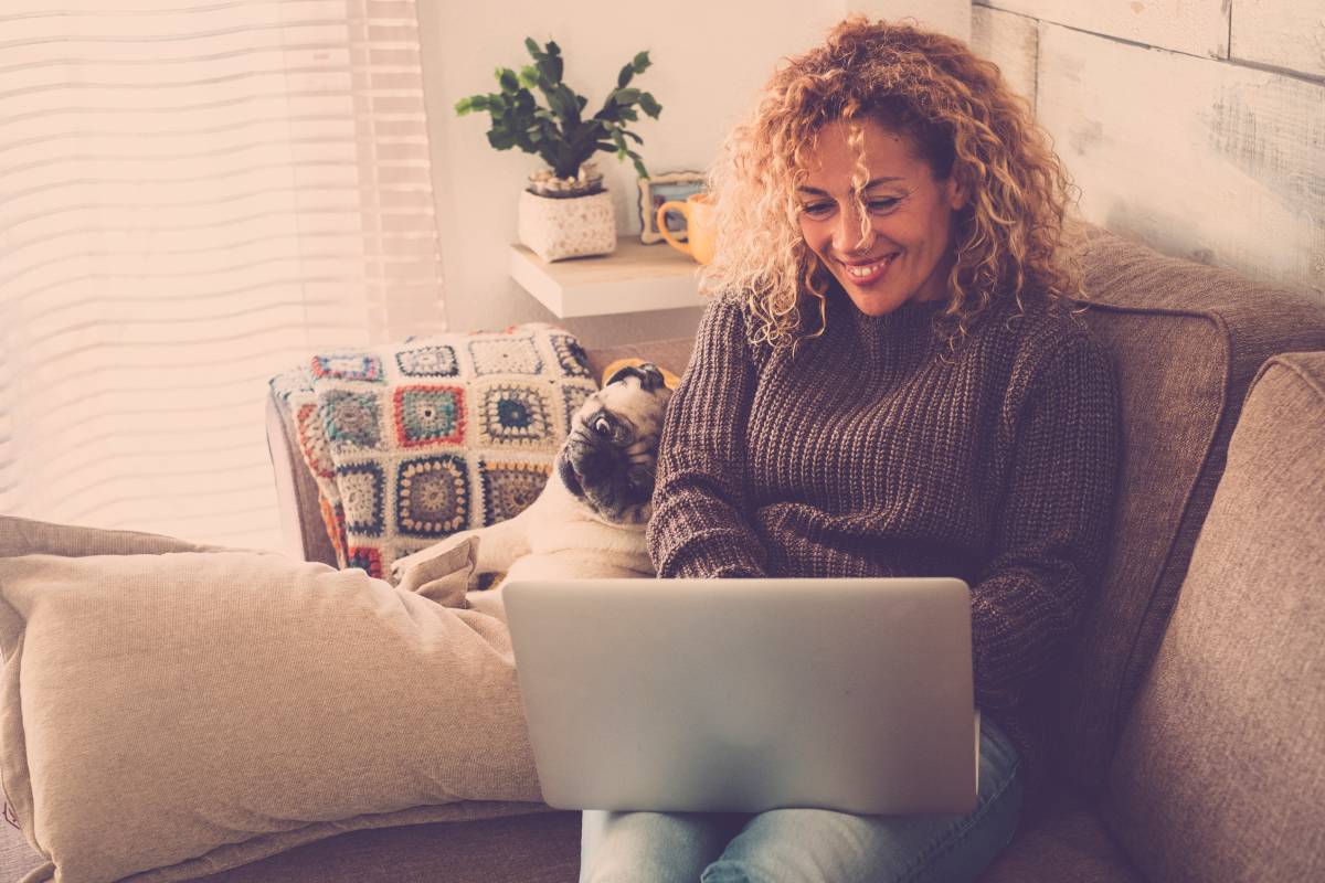 A woman with curly blonde hair working remotely using her laptop
