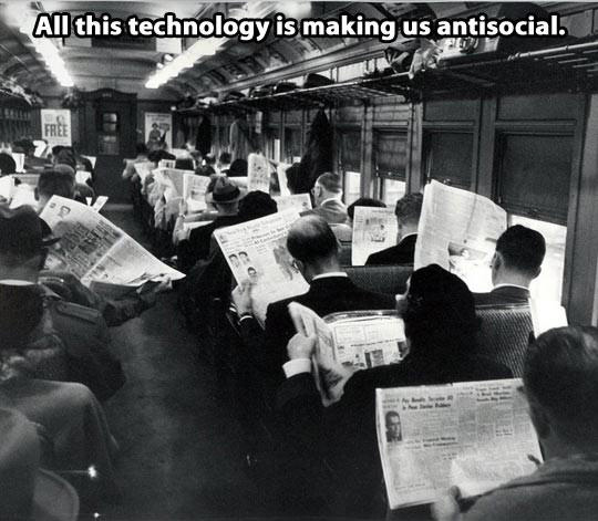 Black and white photograph showing a train full of people reading newspapers