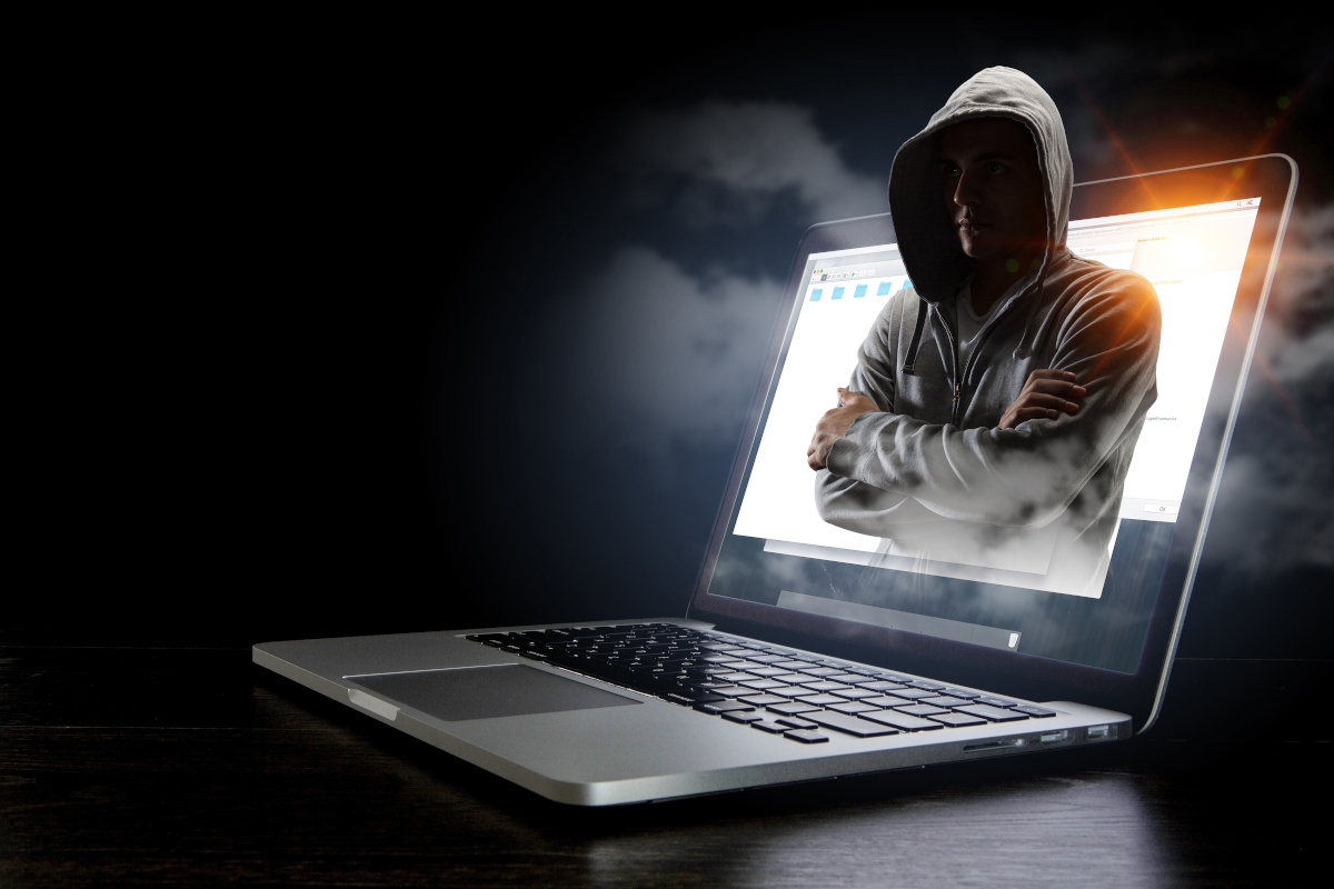 A hooded figure in a gry zip-up hoodie coming out of a laptop
