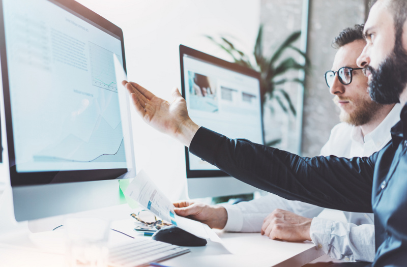 Two Business Men Looking At and Gesturing Towards a Computer Screen