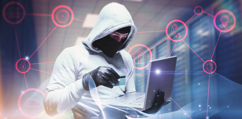 Hacker in white sweatshirt with hood up and a black mask holding a laptop