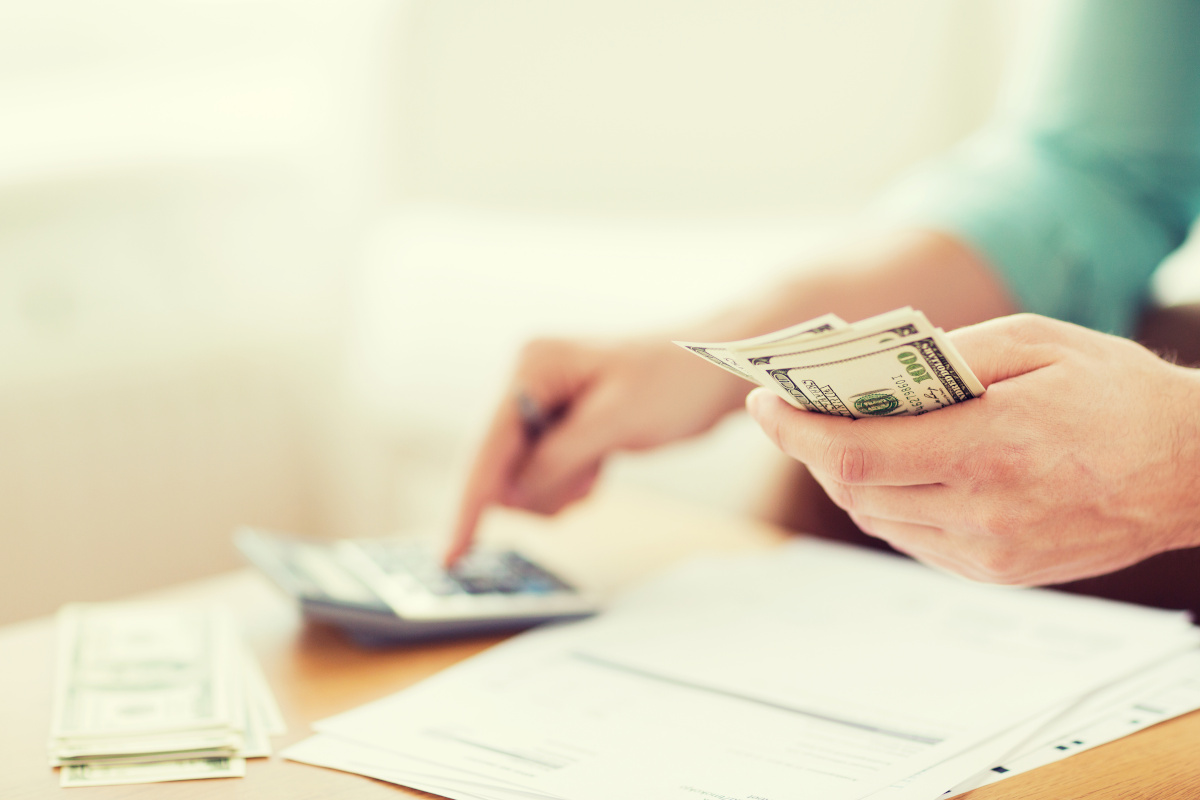 Close Up of Man with Calculator Counting Money