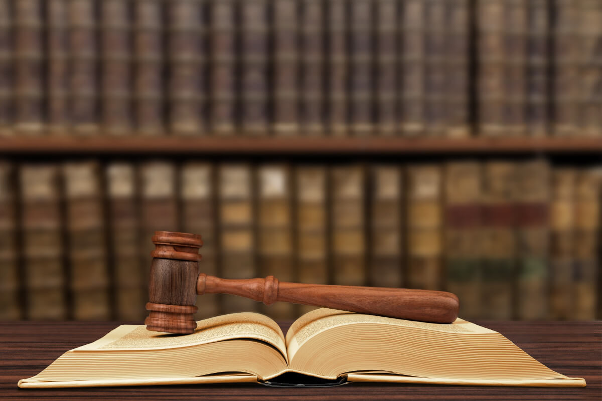 Depiction of law books with an open legal book and judge's gavel