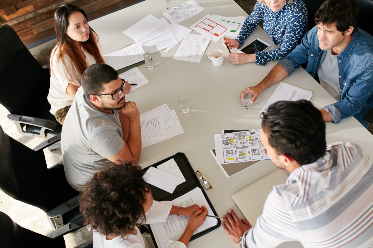 High angle view of creative team sitting around table discussing business ideas.