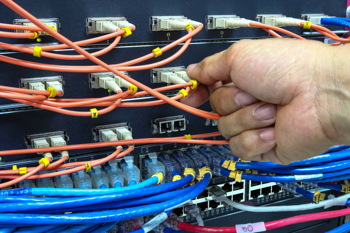 A hand plugging in network cables