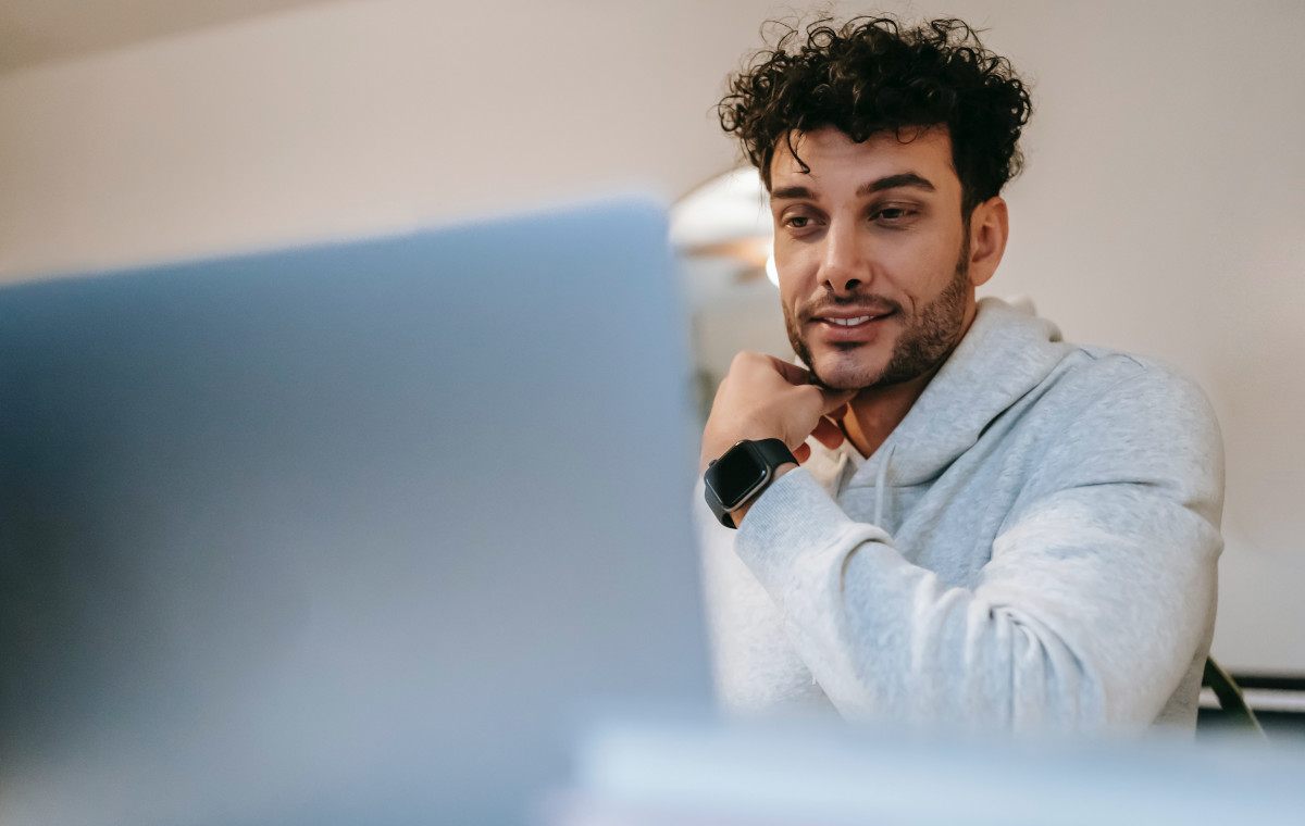 Smiling distance employee in smart watch against laptop at home. Remote work, work from home, telecommute concept.