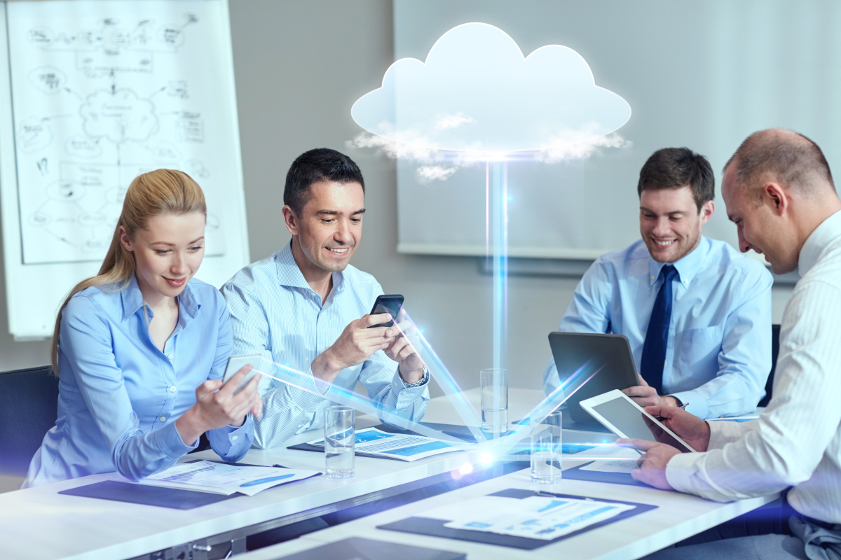 a team of employees sitting around a table interacting with interconnected work devices