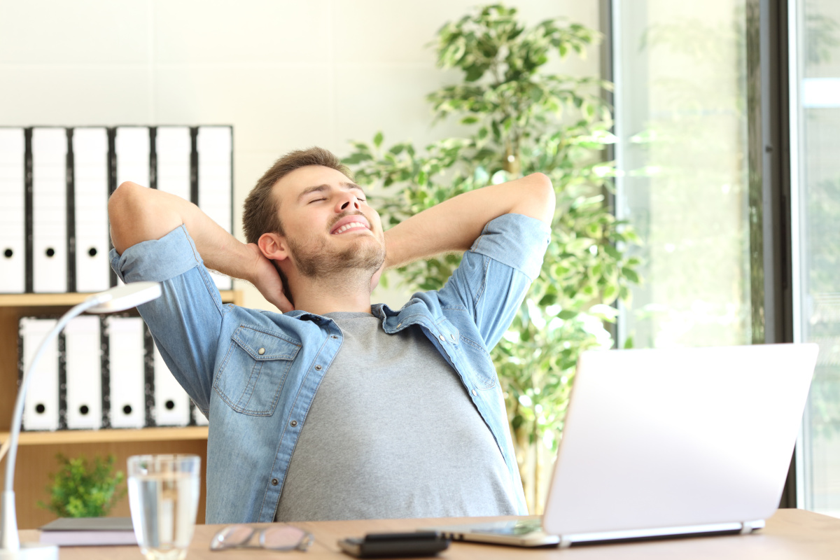 A man reclining in his office chair with his arms behind his head