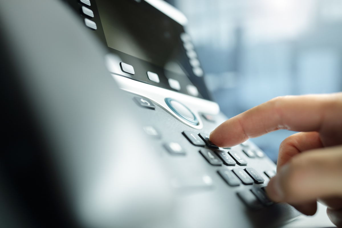 An office desk phone being dialed