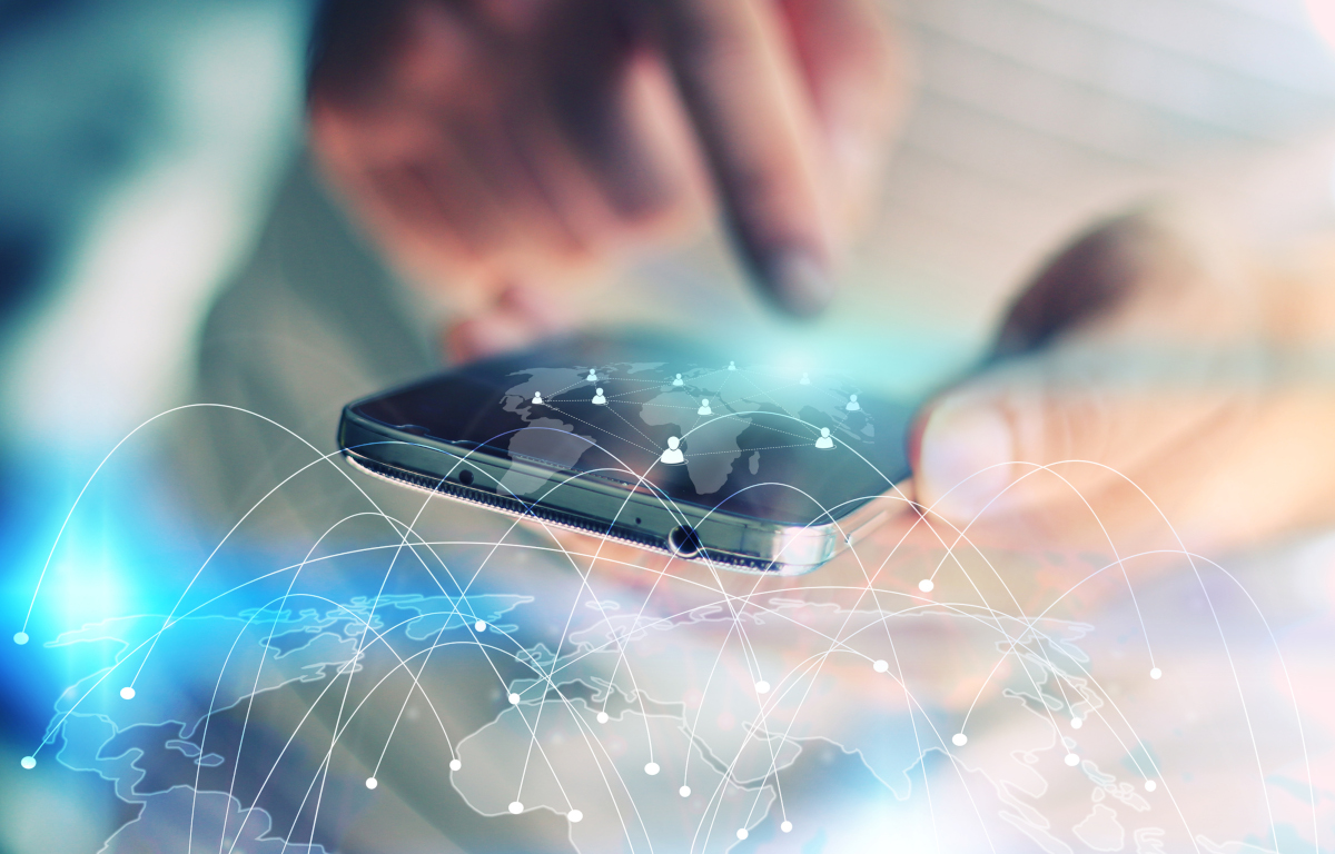 A person holding a smartphone, with an image of a globe in the foreground with dots being connected by curved lines to represent connections