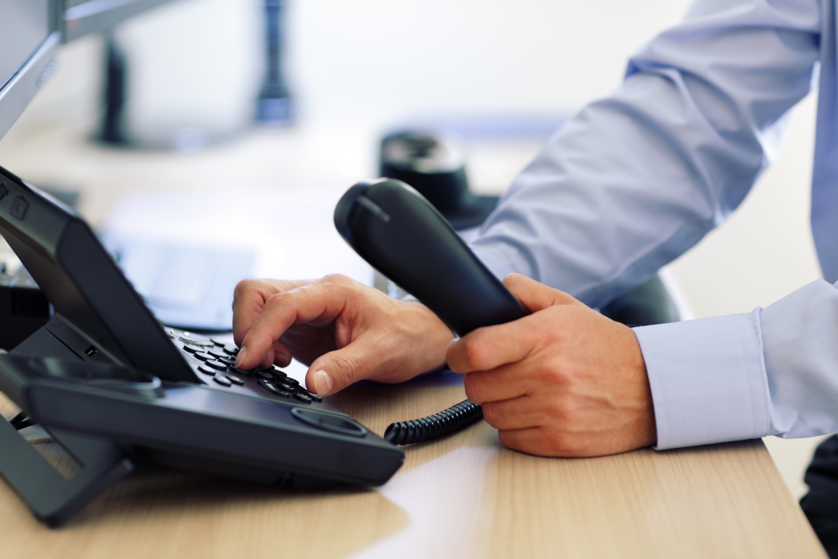 An office desk phone being dialed