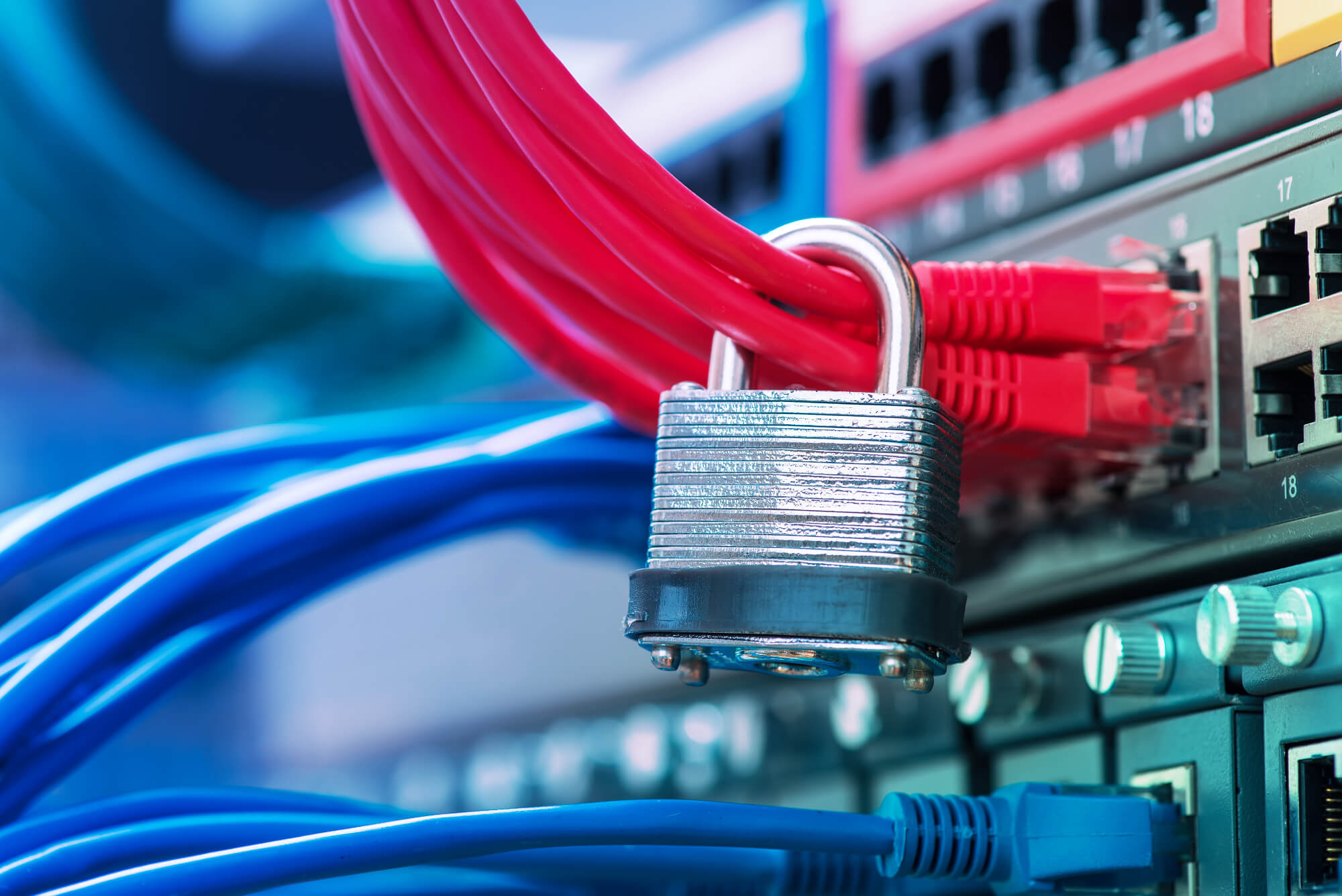 Padlock secured around red Ethernet cables plugged into a server rack