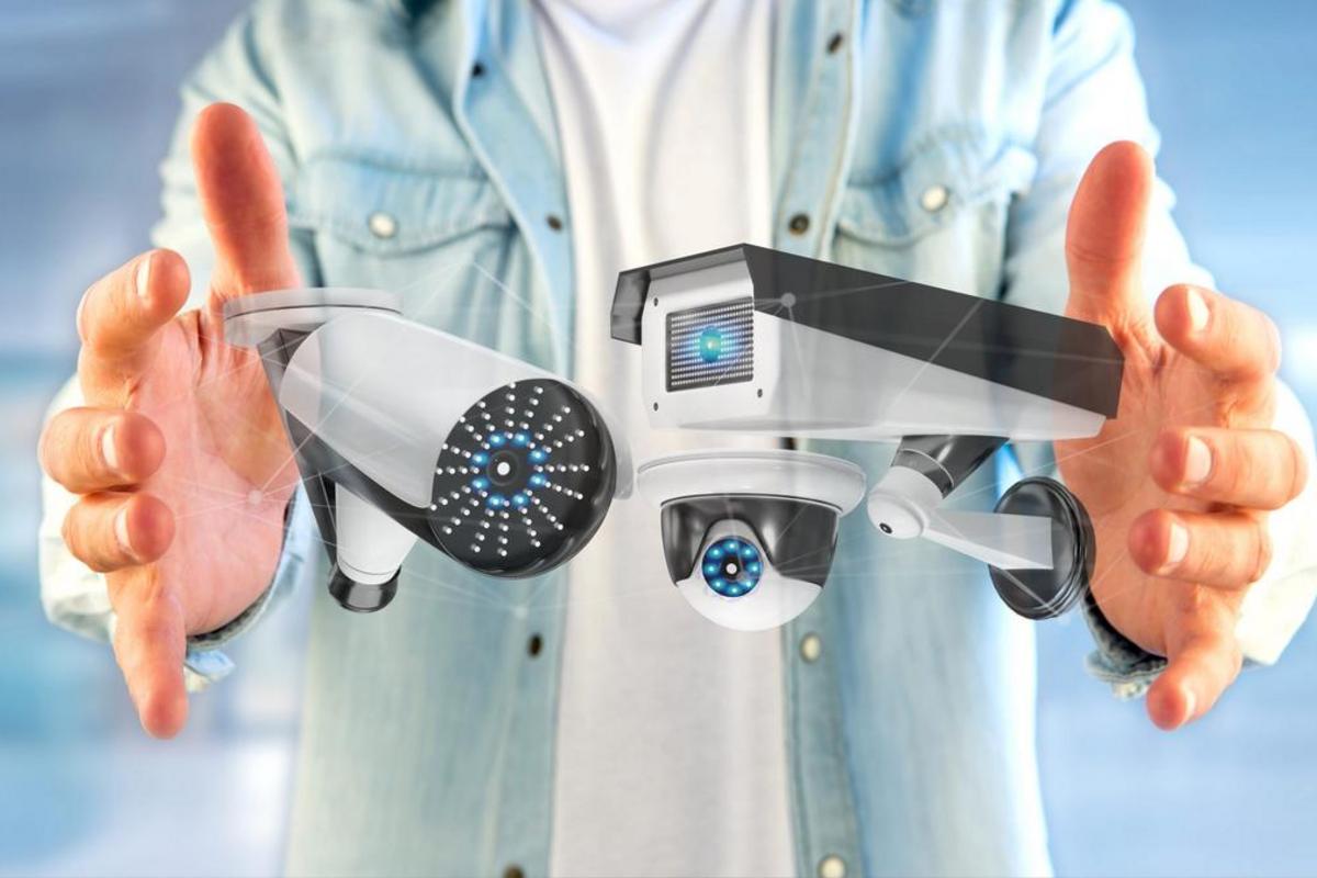 Person holding three types of security cameras with a digital network overlay.