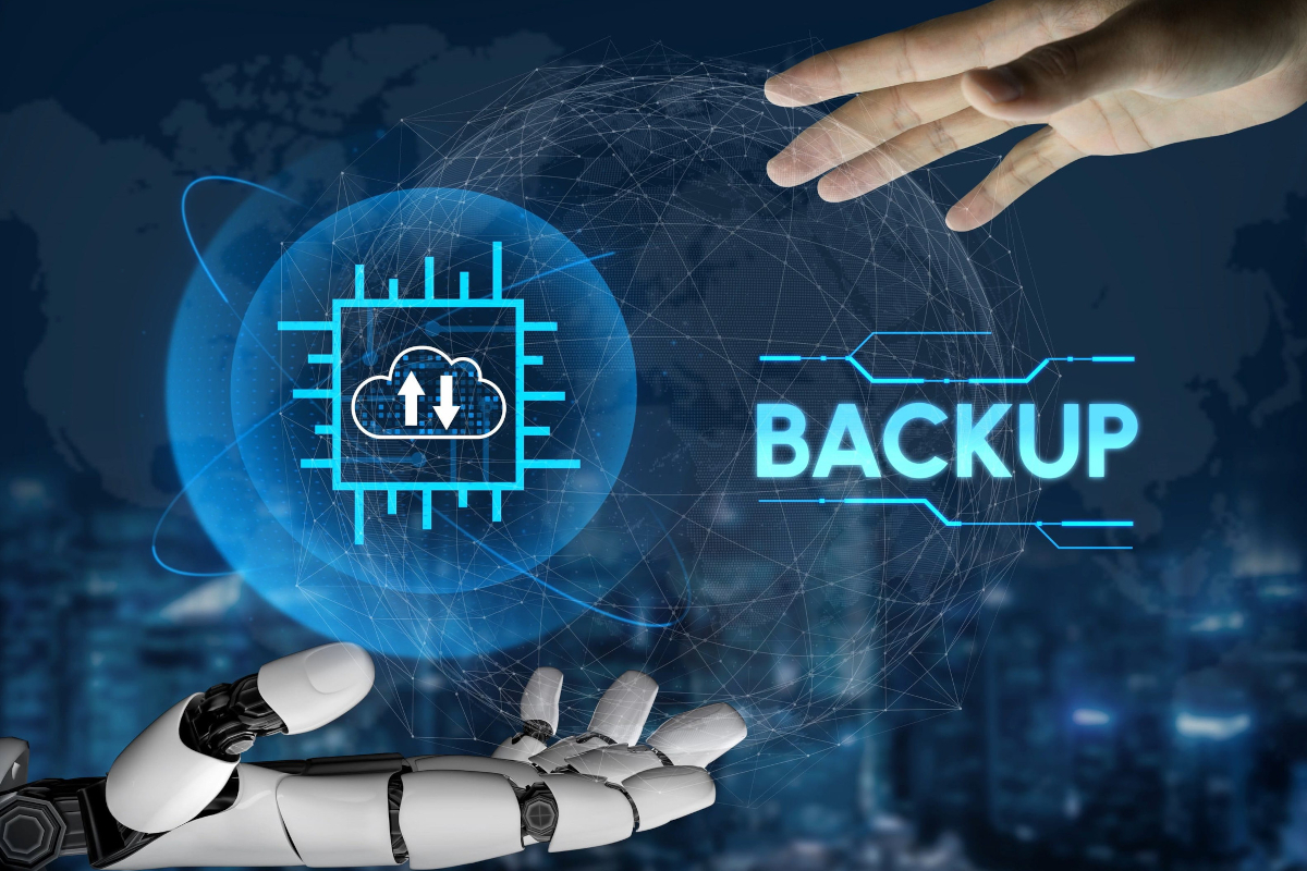 Human hand and robotic hand framing a cloud icon and the word BACKUP on a connected network globe.