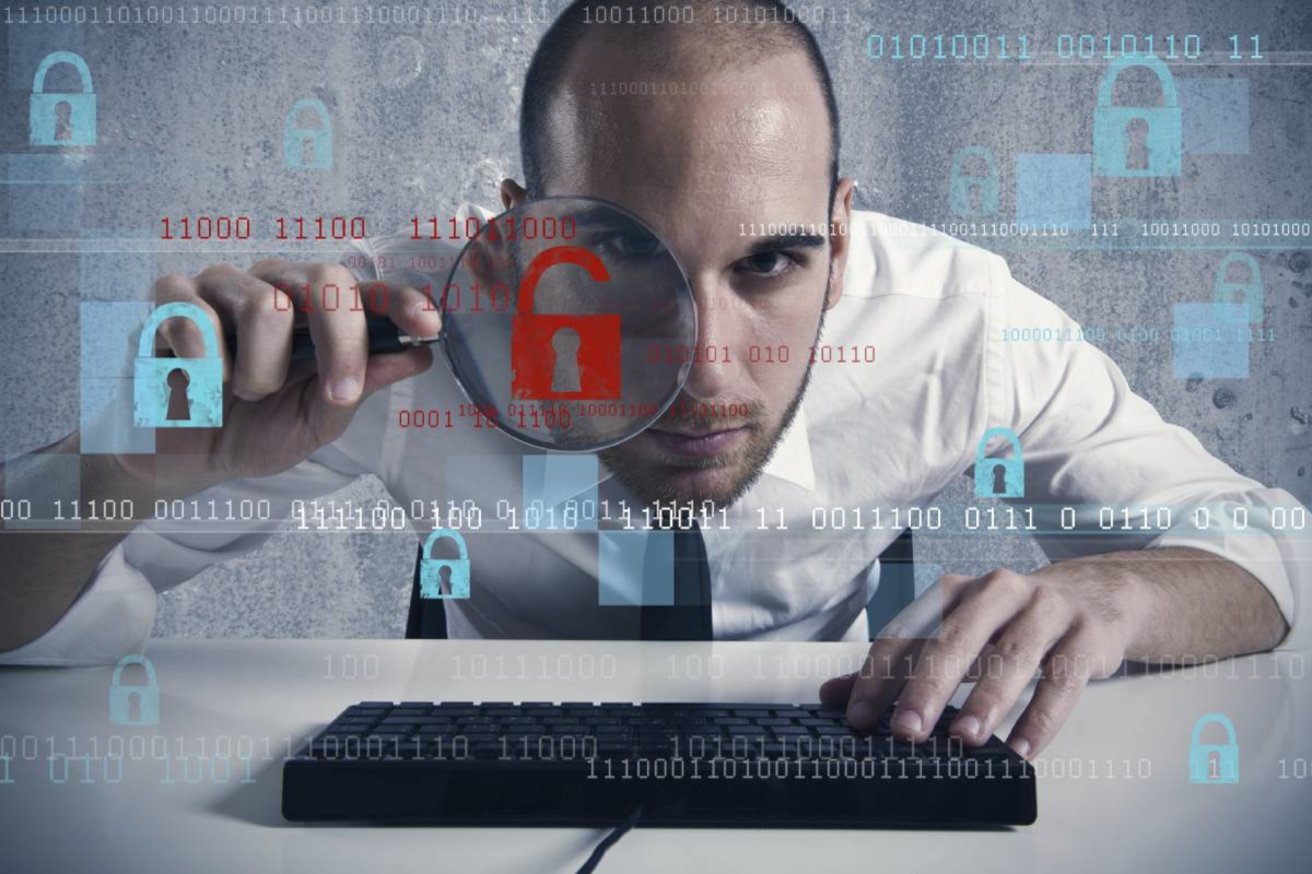 Man working on laptop and using magnifying glass to see better