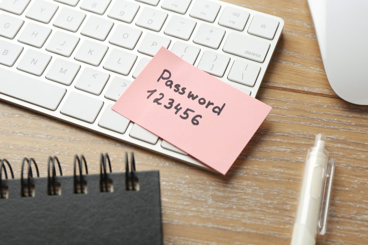 Pink sticky note reading Password 123456 on a white computer keyboard.