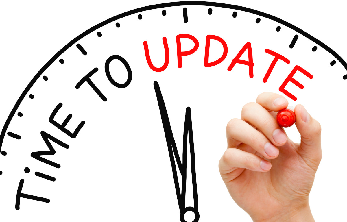 Hand writing 'Time to Update' with red marker on transparent wipe board. Update concept.